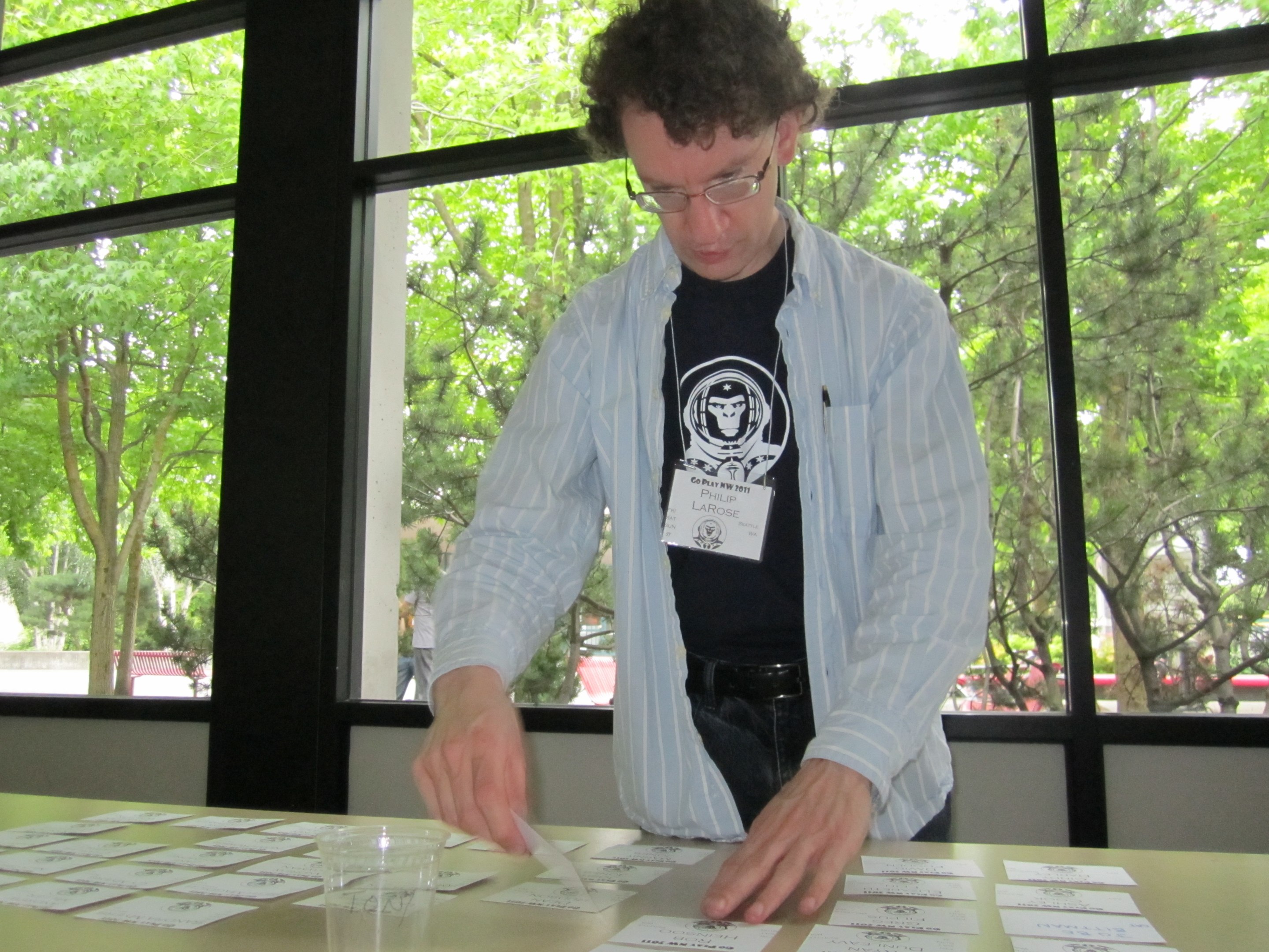Volunteer at a table sorting badges in front of a window